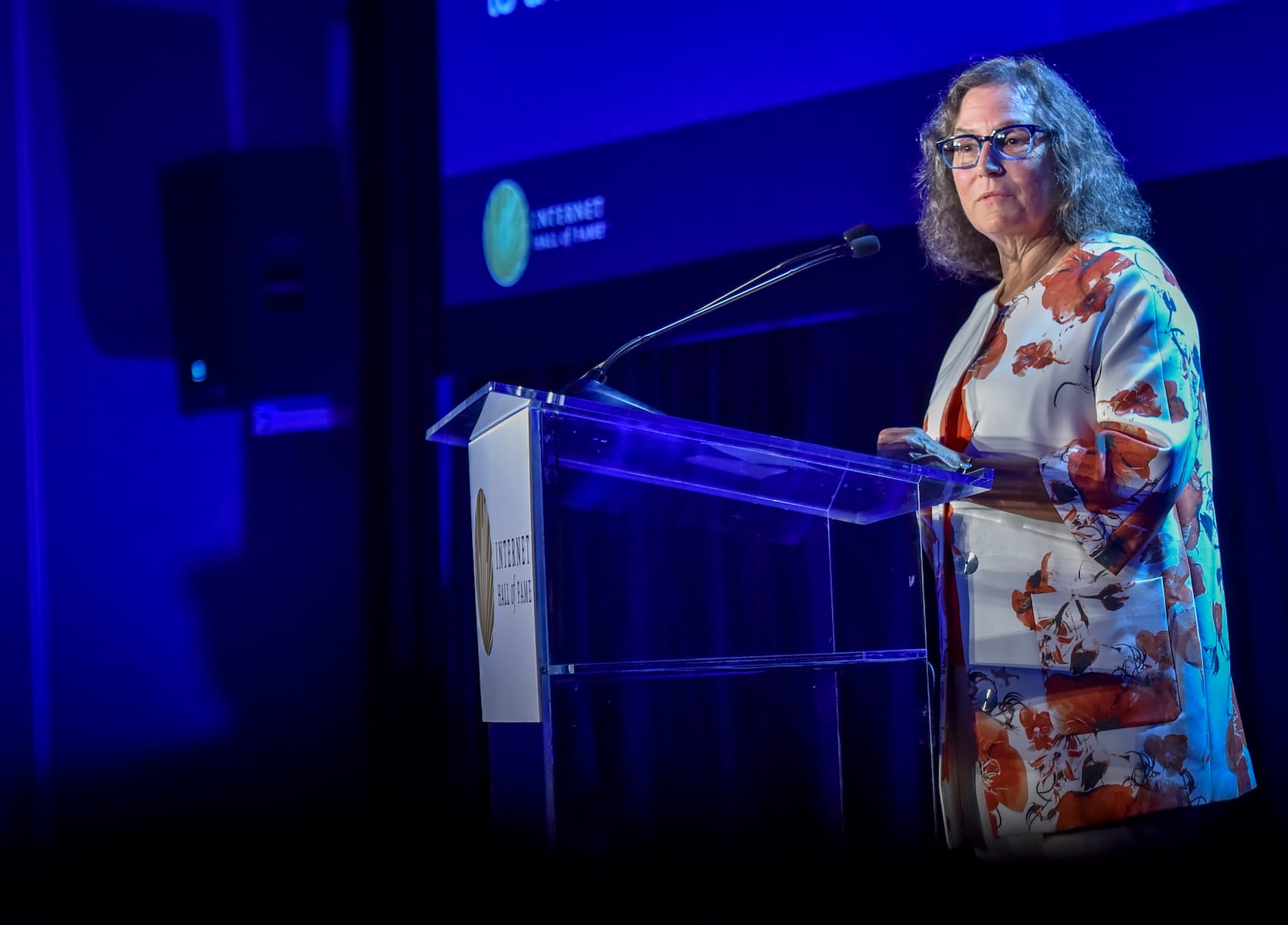 a woman stands on stage giving speech